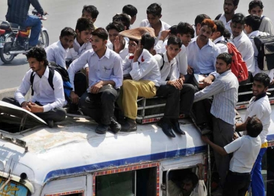 Pakistani students sit on top of an overloaded mini bus.