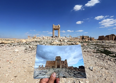 On March 31, 2016, a photographer holds his picture of the Temple of Bel taken on March 14, 2014 in front of the remains of the historic temple after it was destroyed by Islamic State group jihadists in September 2015 in the ancient Syrian city of Palmyra. (Joseph Eid/AFP/Getty Images)