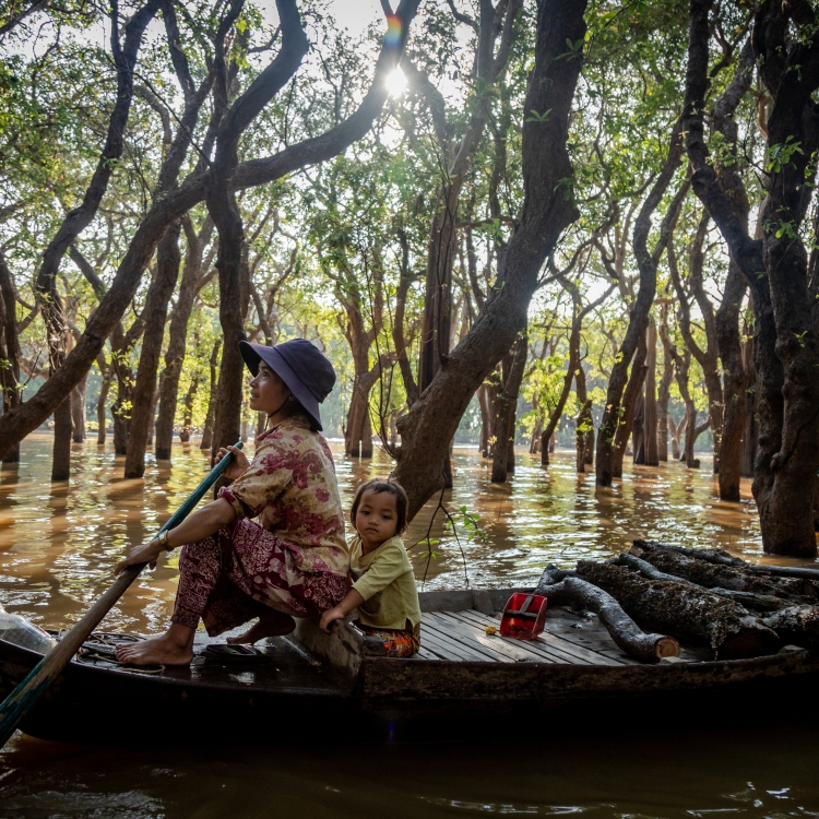 A mother and her daughter collect firewood in a flooded forest in Siem Reap's Kampong Phluk village in December 2018. 