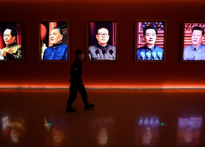 A man walks past portraits of Chinese leaders